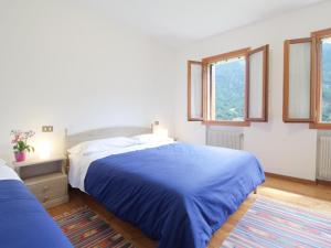 Dormitorio blanco con cama azul y ventanas en Mountain-view holiday home in Cison di Valmarino with garden, en Cison di Valmarino