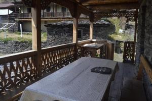a wooden porch with a white table on a balcony at Guesthouse Tushetian Tower in Omalo