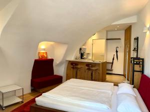 - une chambre avec un lit blanc et une chaise rouge dans l'établissement Appartements im Herzen der Passauer Altstadt, à Passau