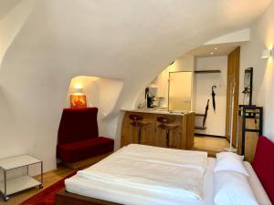 een slaapkamer met een wit bed en een rode stoel bij Appartements im Herzen der Passauer Altstadt in Passau