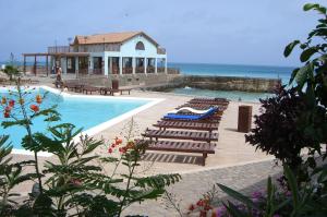 a swimming pool with lounge chairs and the ocean at Porto Antigo Two Bed Apartment with Sea View in Santa Maria
