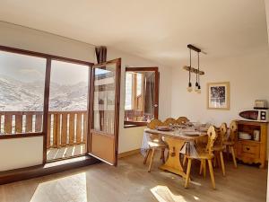uma sala de jantar com uma mesa e uma varanda com montanhas em Appartement Les Menuires, 3 pièces, 6 personnes - FR-1-344-789 em Les Menuires