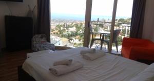Un dormitorio con una cama blanca con toallas. en Panoramic Holidays - Standard 71, en Peyia