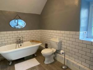 a bathroom with a tub and a toilet and a sink at Farmhouse Cottage set in beautiful countryside in Oswestry