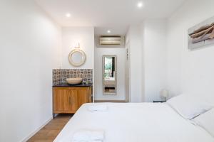 a white bedroom with a large bed and a mirror at Chez Jacques par Dodo-a-Cassis in Cassis