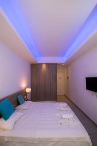 a bedroom with a large white bed with blue lights at Flora Maria Hotel in Ayia Napa