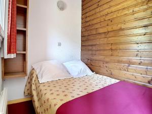 Zimmer mit einem Bett mit einer Holzwand in der Unterkunft Appartement skis aux pieds avec balcon et parking - FR-1-344-880 in Les Bruyères