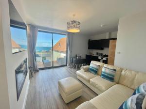 a living room with a couch and a view of the ocean at Coastline Retreats - Stunning Balcony Apartment with Sea Views - Alice in Wonderland Themed Secret Room - Luxury Copper Bath in Master Bedroom in Southbourne