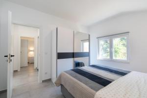 biała sypialnia z łóżkiem i oknem w obiekcie The Plaza Apartment w mieście Prižba