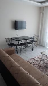 a living room with a table and chairs and a flat screen tv at Geyikli suit apart3 in Geyikli