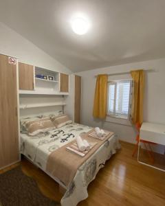 Schlafzimmer mit einem Bett, einem Tisch und einem Fenster in der Unterkunft Apartmani Sirius in Silba