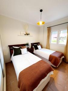 two beds sitting in a room with two windows at Bajo Amparo Altaona Golf in Murcia