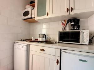a white kitchen with a sink and a microwave at Studio Les Menuires, 1 pièce, 3 personnes - FR-1-344-931 in Les Menuires