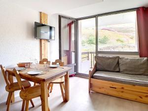 a dining room with a table and a couch at Studio rénové proche pistes avec balcon, 3 couchages - FR-1-344-948 in Les Menuires