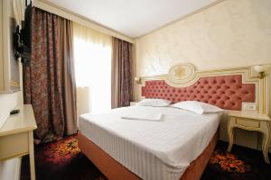 Hotel Belona في إيفوري نورد: غرفة نوم بسرير كبير مع اللوح الأمامي الأحمر