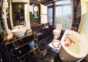 a bathroom with a toilet and a sink and a tub at Palmier Hotel - Art House Da Nang in Danang