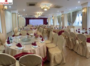 a banquet hall with tables and chairs and a screen at White Hotel in Hà Tĩnh