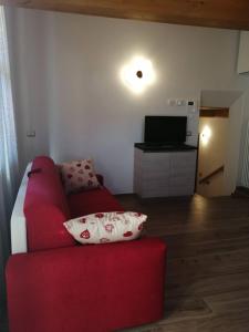 ein Wohnzimmer mit einem roten Sofa und einem TV in der Unterkunft Cadore Luminoso appartamento in Calalzo