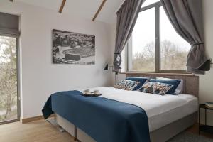a bedroom with a bed with blue sheets and windows at Korona Bieszczad in Wetlina