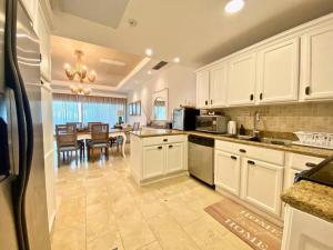 a kitchen with white cabinets and a dining room at Stylish Lux Beach Condo Aquamarina Cap Cana in Punta Cana