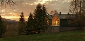 a house on a hill with the sunset in the background at Korona Bieszczad in Wetlina