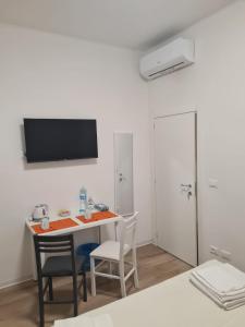um quarto com uma mesa e cadeiras e uma televisão na parede em LU.NA em Bolonha