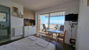 a room with a bed and a kitchen with a balcony at Appartements front de mer Royan in Royan