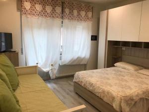 1 dormitorio con 1 cama y una ventana con cortinas en A CASA DI LETY, en Tarvisio