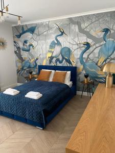 a bedroom with a blue bed with a mural of birds at Heron Apartment blisko Starówki NOWO OTWARTY in Gdańsk