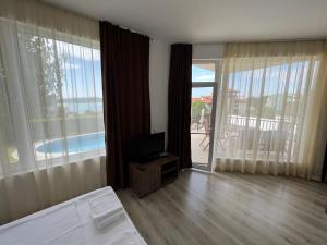 a bedroom with a bed and a television and a balcony at Family Hotel Dreams in Sozopol +114 photos