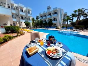 a table with breakfast food next to a swimming pool at Summer rose hotel in Side