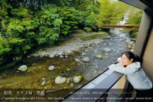 a woman taking a picture of a river at Tatsuta Ryokan in Izu
