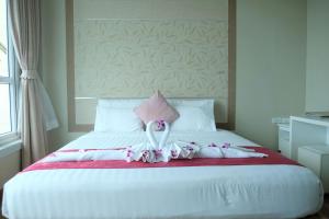 a white bed with a pink pillow and flowers on it at The Beach Front Resort, Pattaya in Pattaya Central