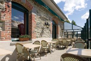 a patio with tables, chairs, and tables in front of a building at Auberge de la Baie in Ardevon