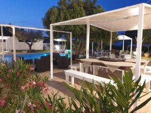 a white pavilion with a table and chairs next to a pool at AGRI ART in San Benedetto Ullano