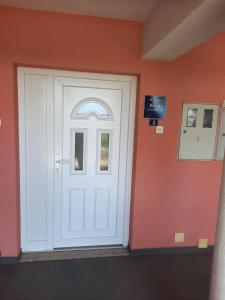 białe drzwi w pokoju z pomarańczową ścianą w obiekcie Apartman Kapelica w mieście Labin