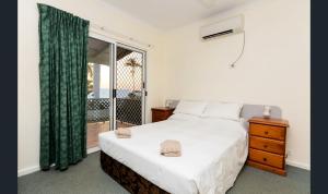 a bedroom with a bed and a dresser at Cable Beachside Villas in Broome