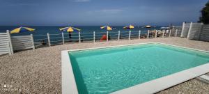 a swimming pool next to a beach with umbrellas at Camping Victoria in Capaccio-Paestum