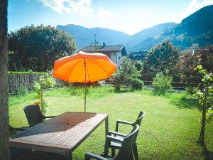 una mesa de madera con una sombrilla naranja en un patio en Appartement Birgla, en Ramsau im Zillertal