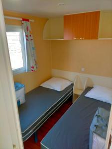 two beds in a small room with a window at EURL kaza évasion services in Cabariot