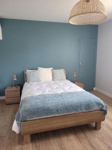 a bedroom with a large bed with a blue wall at La Mosloise in Mosles