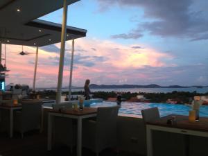 a woman standing on the roof of a restaurant with a pool at Action Point Weight loss and Fitness Resort in Rawai Beach