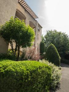 a house with bushes and trees in front of a building at appartement du Bellay in Sarlat-la-Canéda