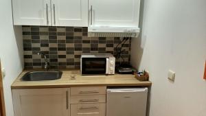 a kitchen with a sink and a microwave at Casa do Pelourinho - T0 in Loriga