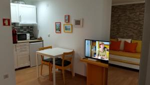 ein Wohnzimmer mit einer Küche und einem Tisch mit einem TV in der Unterkunft Casa do Pelourinho - T0 in Loriga