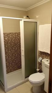 a bathroom with a toilet and a glass shower at Casa do Pelourinho - T0 in Loriga