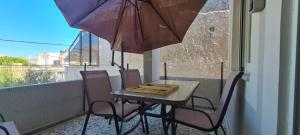 d'une table et de chaises sur un balcon avec un parasol dans l'établissement Μοντέρνα εξοχική κατοικία στην Κωμη, à Kómi