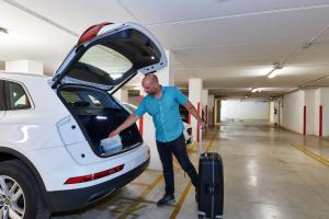 a man is putting his luggage into the open trunk of a car at Wally Residence in Rimini