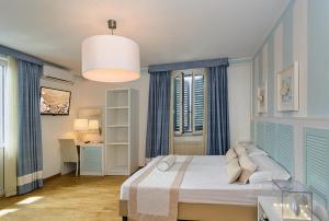 a bedroom with a bed with blue curtains and a desk at Raffaelli Villino Limoni in Forte dei Marmi
