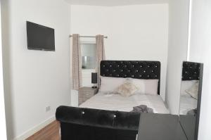 a bedroom with a bed with a black leather couch at Virtue House in Woolwich